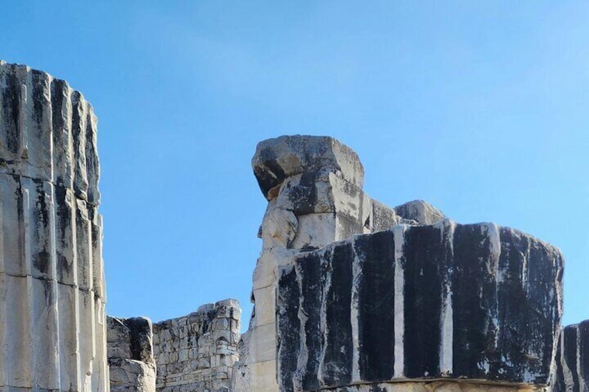 Ancient stone ruins with large, weathered columns and a prominent rock formation. 3