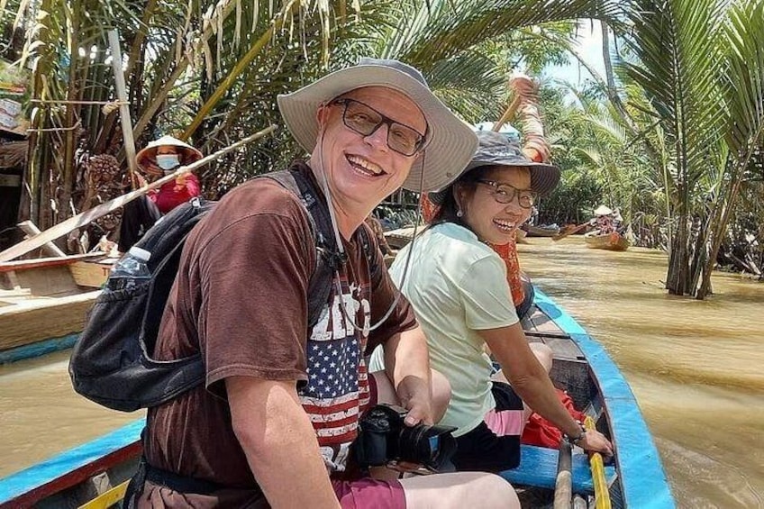 Two people in a boat on a river surrounded by palm trees. 4