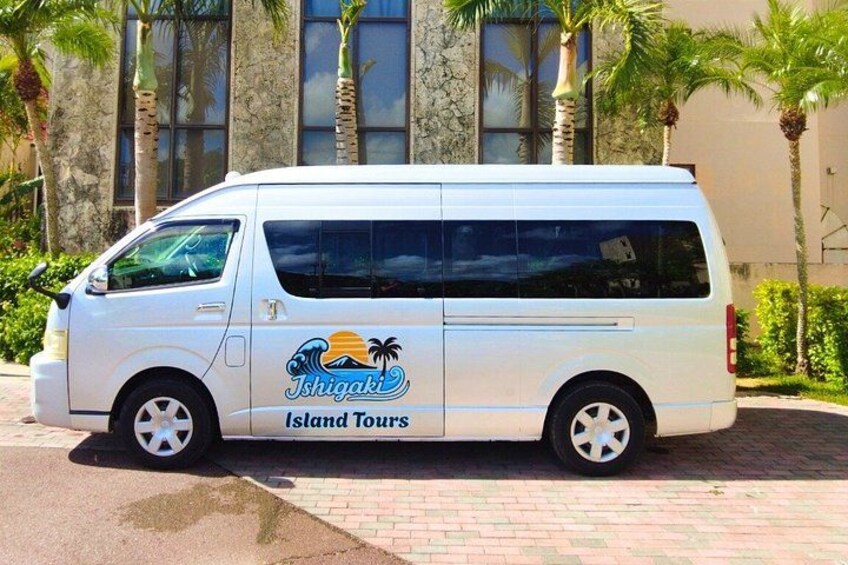 A white van with 'Island Tours' branding parked in front of a building with palm trees. 5