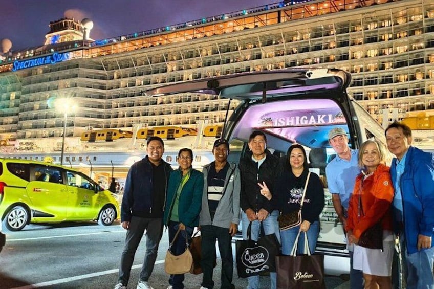 A group of people posing in front of a cruise ship with 'SHIGAKI' written on the side. 2