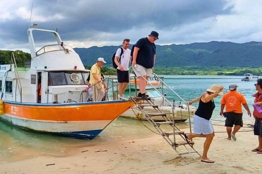 A boat docked at a beach with people boarding and disembarking. 4