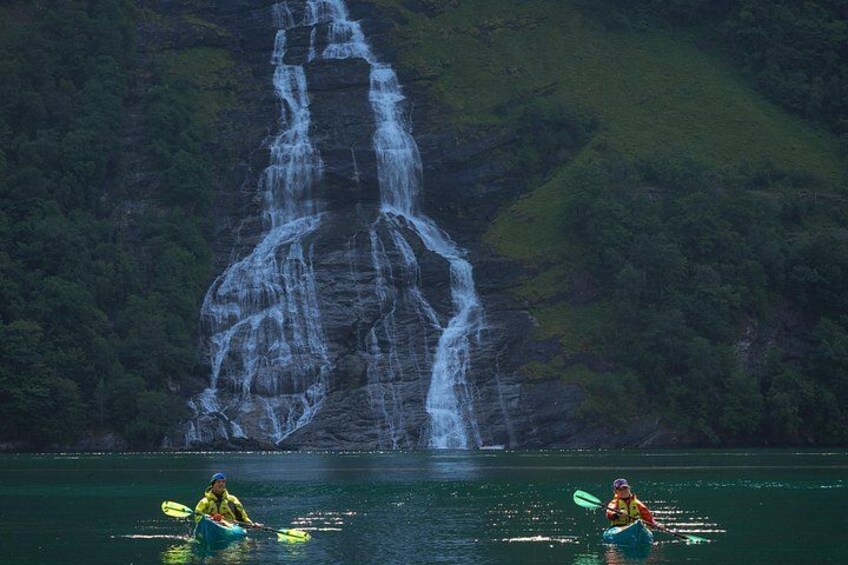 Kayakisti su un lago tranquillo con una cascata sullo sfondo. 2