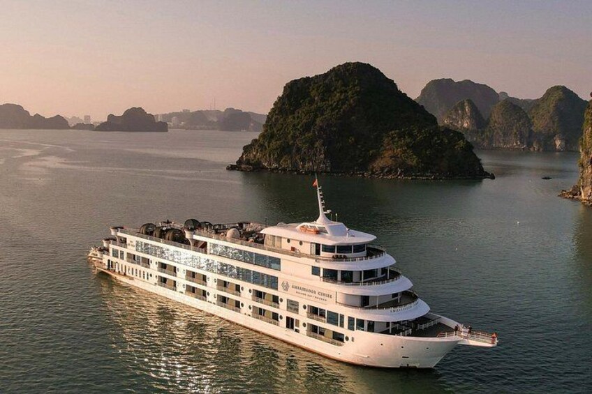 Een groot wit cruiseschip met meerdere dekken, varende langs een groep groene eilanden in het water. 2