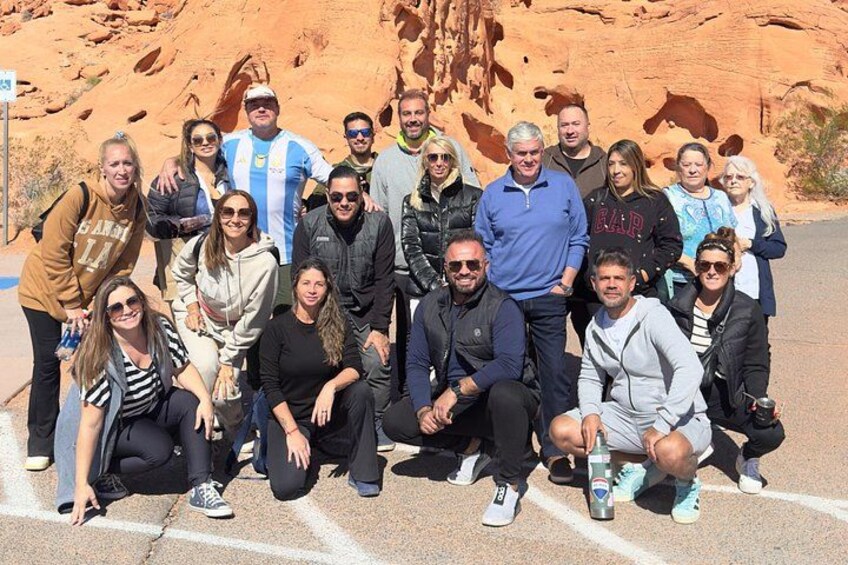 A group of people posing in front of a red rock formation. 3