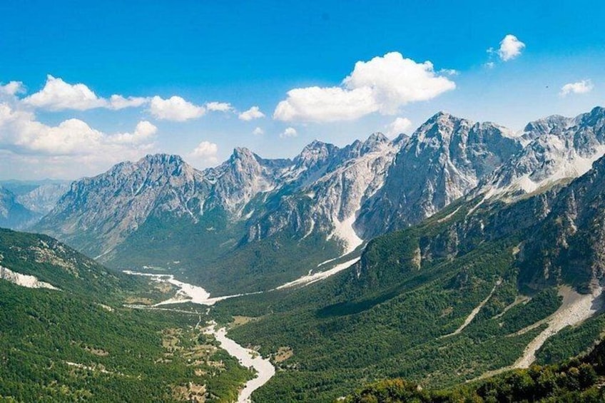 Een bergachtig landschap met een rivier, dichte bossen en ruige toppen. 4