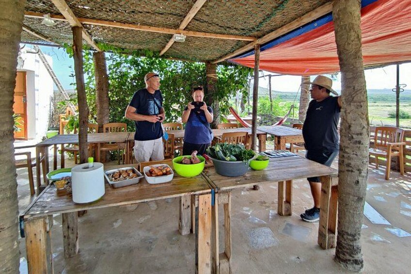 Un espace extérieur aménagé pour les repas, avec des tables et des chaises en bois, et un toit abrité. 3