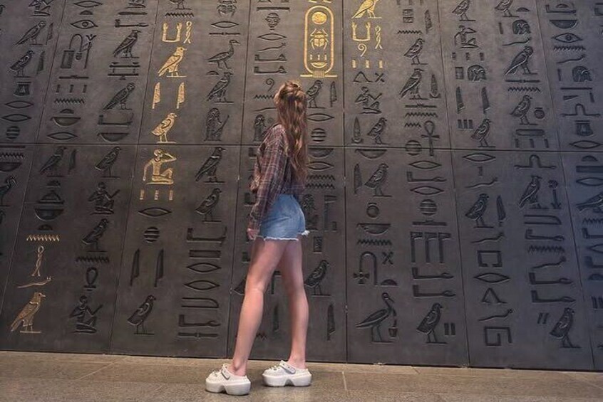 A person standing in front of a wall with hieroglyphs. 3