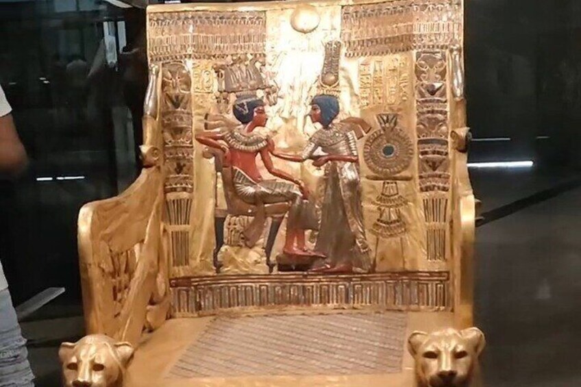 A golden Egyptian sarcophagus with hieroglyphics and two figures, one seated and one standing. 5