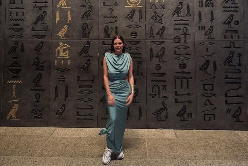 A person standing in front of a wall with ancient Egyptian hieroglyphs. 2