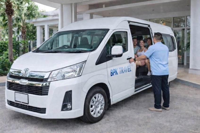 A white van with 'BPK TRAVEL' written on the side parked in front of a building with palm trees. 4