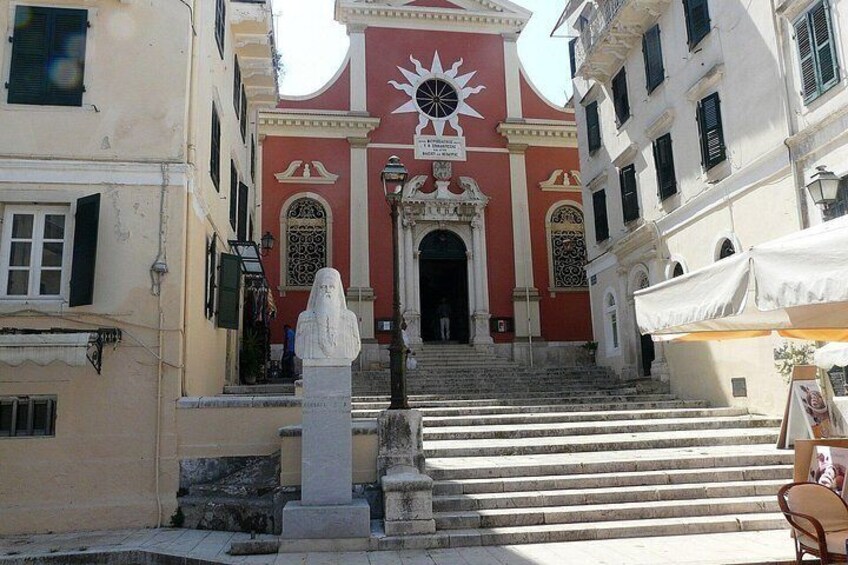 A building with a red facade, a statue, and a staircase leading to an entrance. 5