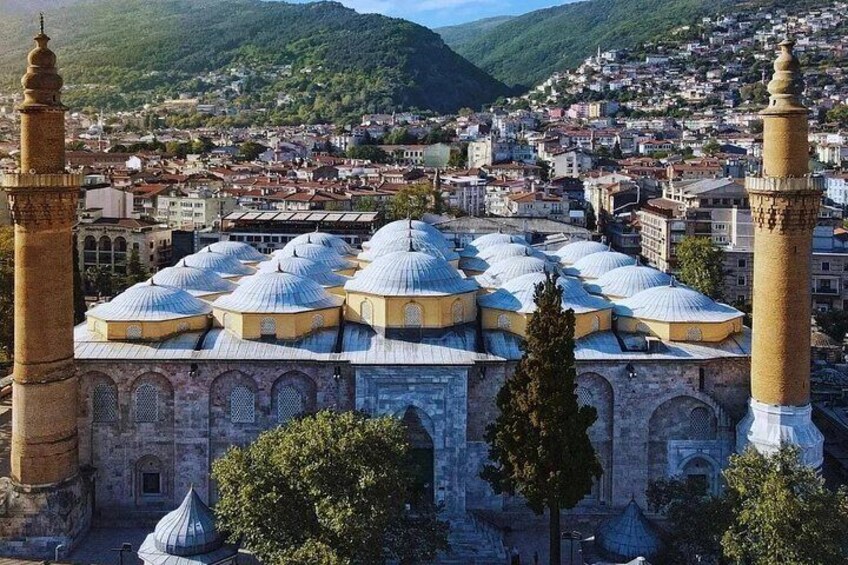 A mosque with multiple domes and minarets, surrounded by a cityscape and hills. 2