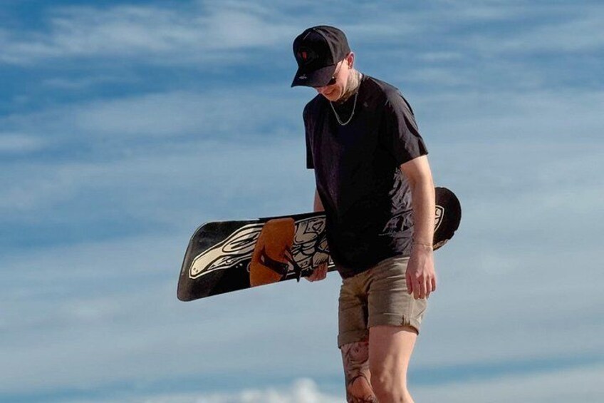 Una persona sostiene una tabla de snowboard contra un cielo despejado. 1