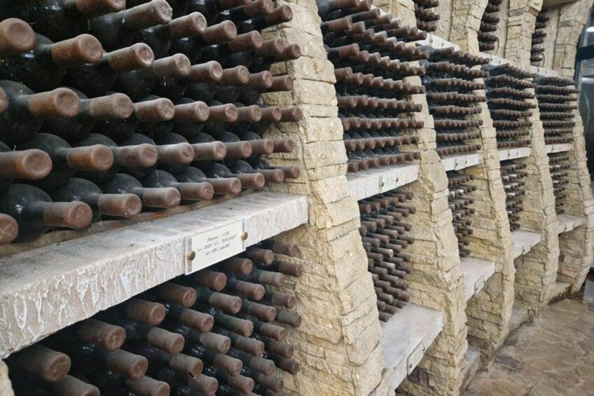 Filas de botellas de vino almacenadas en estantes de piedra. 3