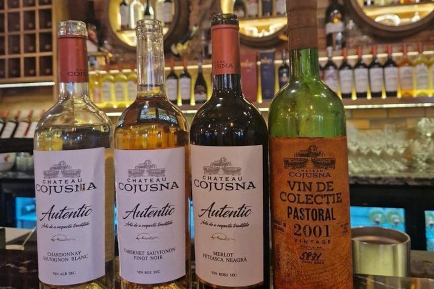 Cuatro botellas de vino Chateau Cojusa sobre una barra. 4