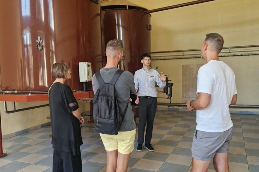 Un grupo de personas en una habitación con tanques industriales grandes y una cámara sobre un trípode. 2