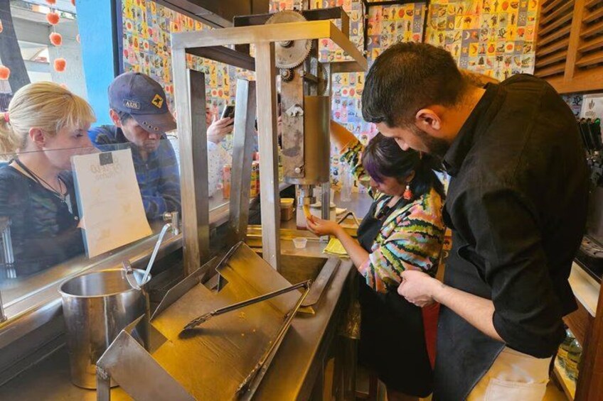 Un stand de nourriture avec un comptoir en métal, une personne qui prépare les plats et un client. 1