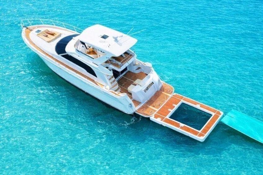 A white yacht with a covered deck and a small platform extending into the water. 1