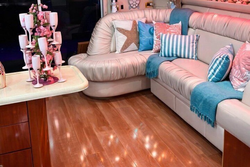 A plush sofa with a starfish pillow, striped pillows, and a pink floral arrangement on a wooden floor. 4