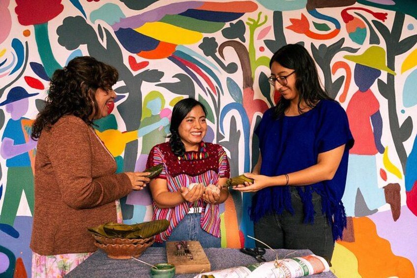 Tres personas interactuando con un mural colorido, un tazón y un plato con comida. 5