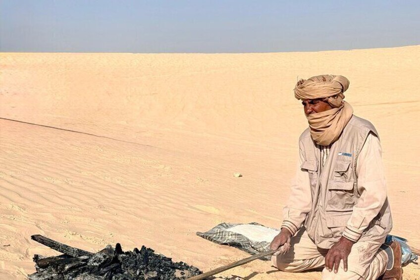 En person som sitter på en sanddyn i en öken. 3