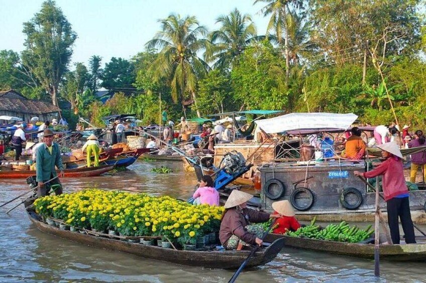 A river with boats carrying produce, surrounded by palm trees and other vegetation. 1