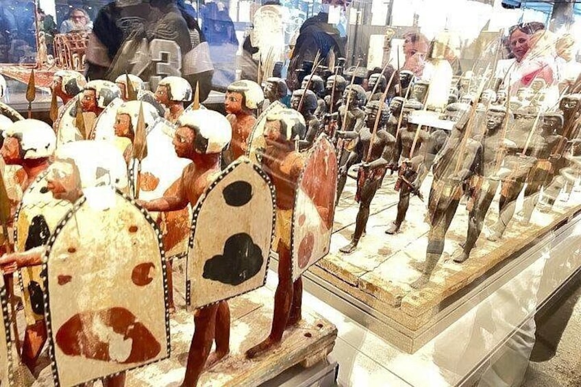 Eine Museumsvitrine mit antiken Figuren von Kriegern, Schilden und Speeren. 2