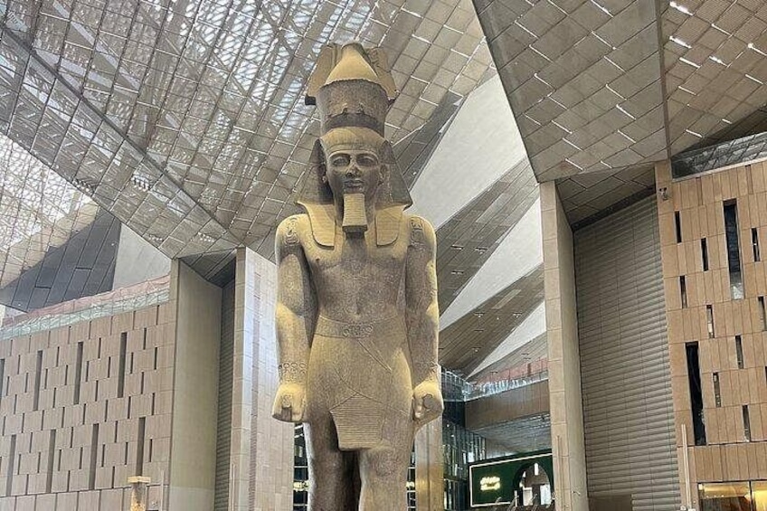 Eine große, antike ägyptische Statue in einem modernen Gebäude mit Glasdach. 4