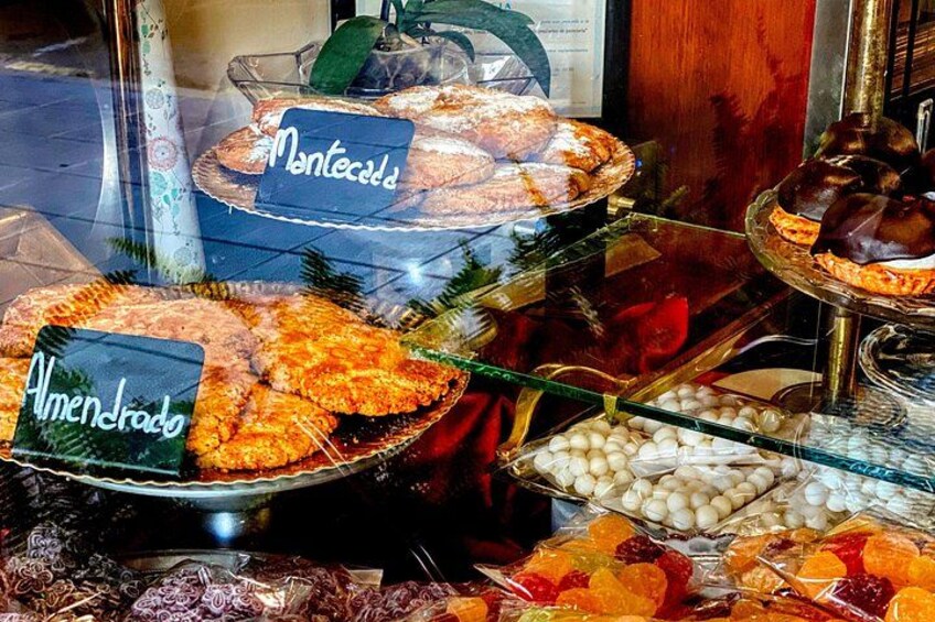 A display of various baked goods and pastries in a glass case with labels. 4