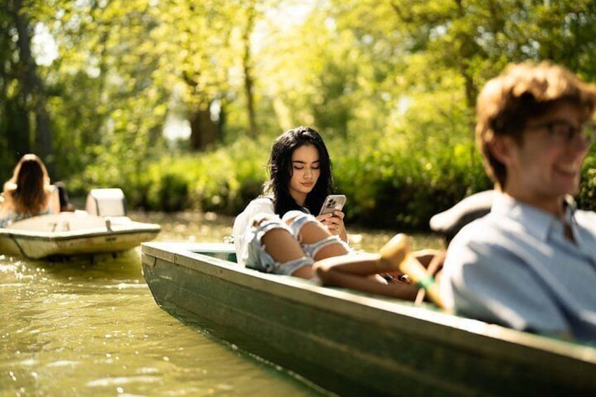 People in a rowboat on a river, surrounded by greenery. 5