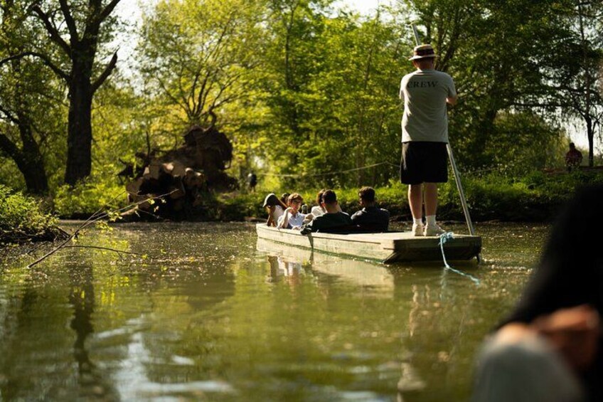 A group of people in a small boat on a calm river, surrounded by lush greenery. 3