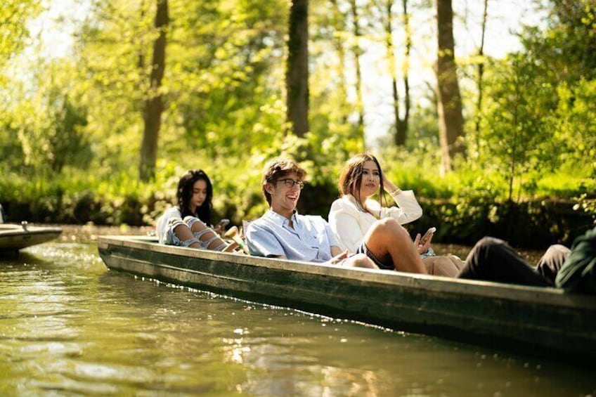 People in a rowboat on a calm river surrounded by lush greenery. 3