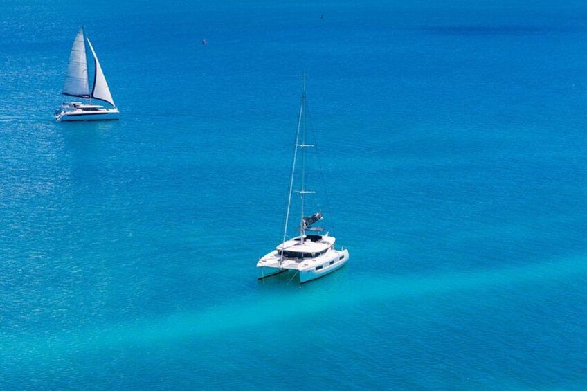 A sailboat and a yacht in turquoise waters. 5
