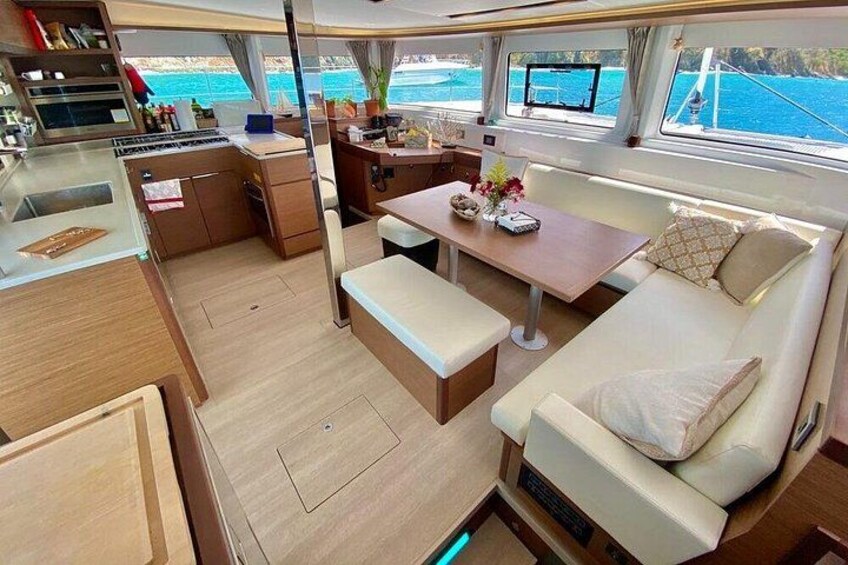 A yacht interior with a dining area, a sofa, and a kitchen. 2