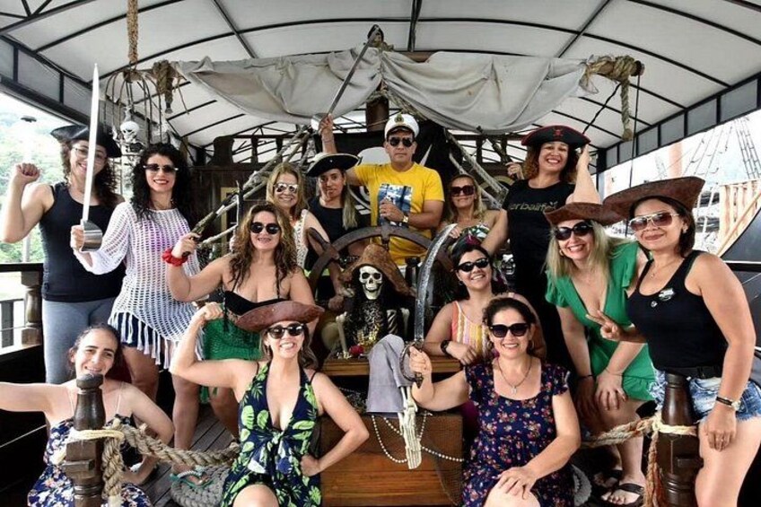 A group of people on a boat, some wearing pirate costumes, with a skull decoration and ropes. 4