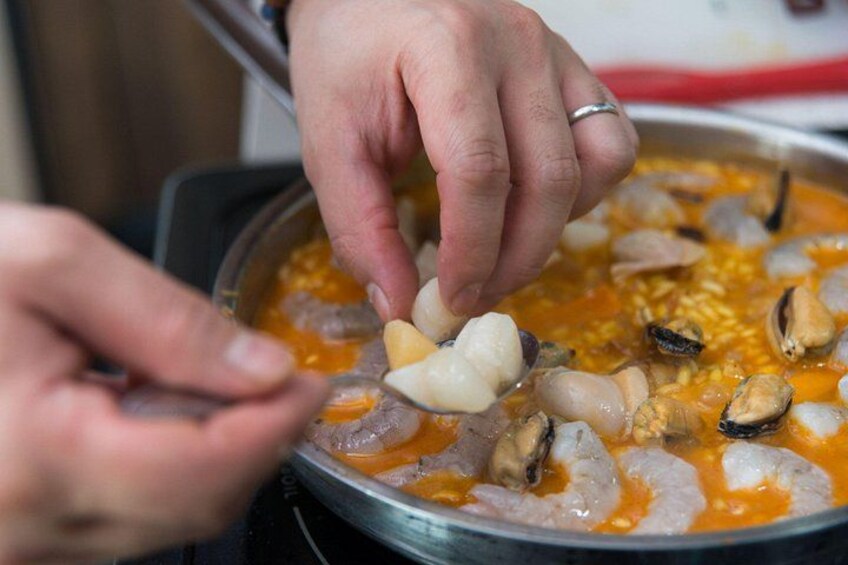 A person cooking seafood in a pan. 2