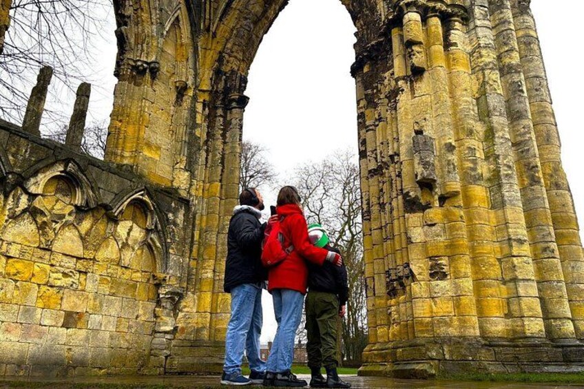 A historical stone archway with intricate carvings, standing in a grassy area. 2