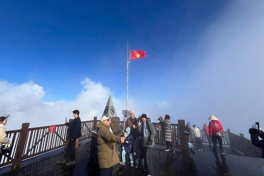 A group of people on a wooden platform with a flagpole and a flag. 2