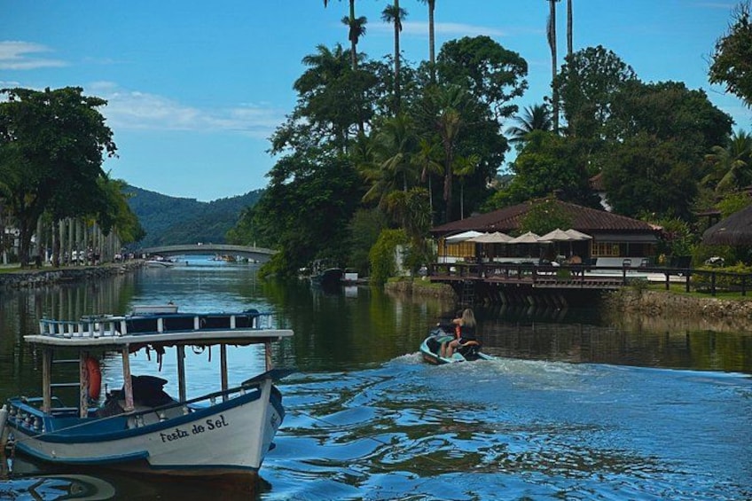 A river with a boat named 'Festa do Sol' and a person wakeboarding. 3