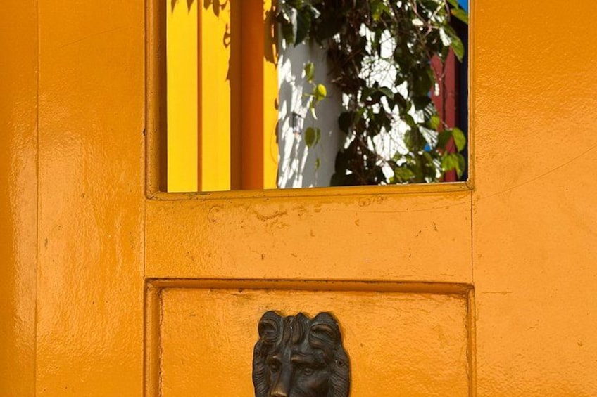 A yellow door with a window and a decorative metal plaque. 4