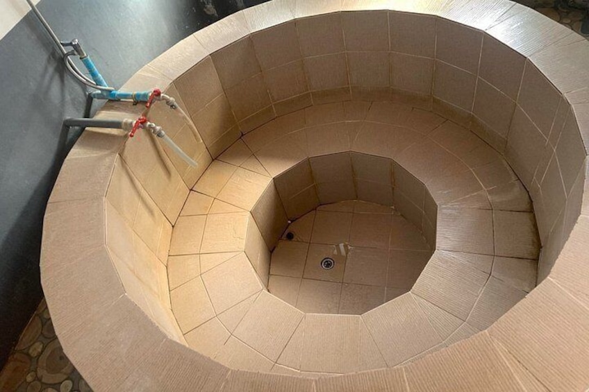A spiral staircase with beige tiles and a central drain. 1