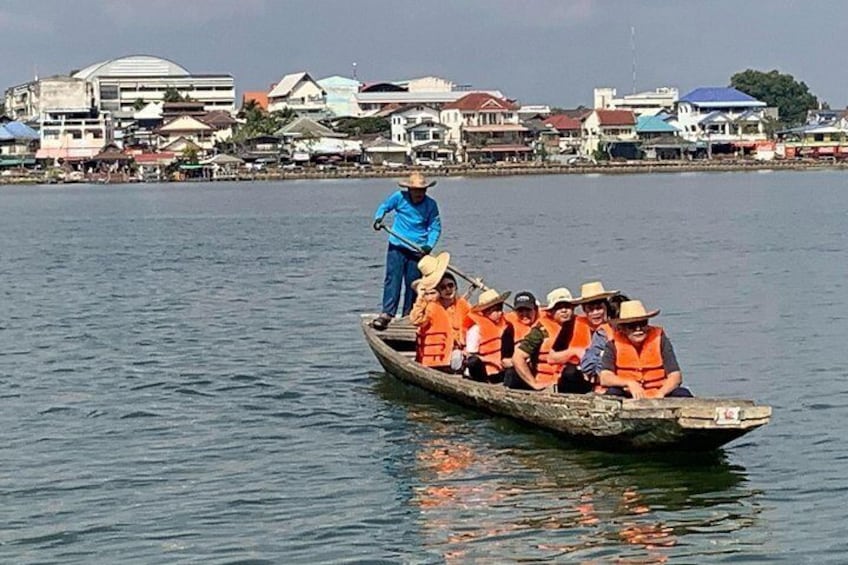 A boat with several people wearing orange life jackets on a calm body of water. 1