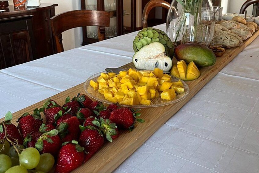 En fruktfat med jordgubbar, vindruvor, mango och ananas, serverat på en träbricka. 4