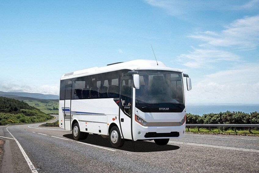 A white bus on a road with a scenic landscape in the background. 3