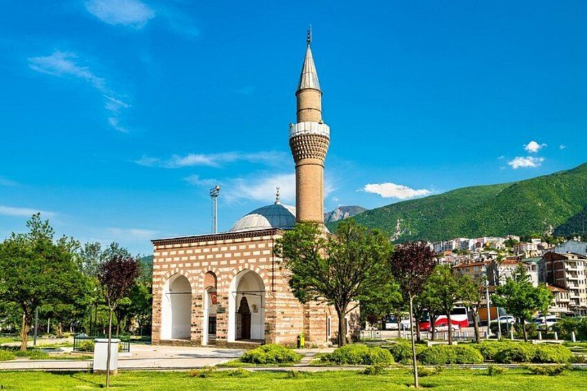 A mosque with a tall minaret, surrounded by greenery and a clear blue sky. 3
