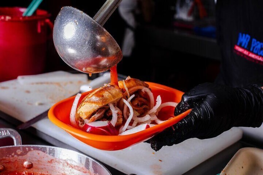 A person cooking a sandwich with a spoon on an orange plate. 1