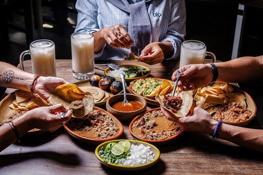 Un grupo de personas cenando en una mesa con diferentes platos y bebidas. 4