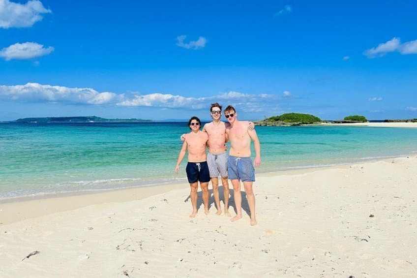 En strand med krystalklart turkisblåt vand og en fjerntliggende ø. 4