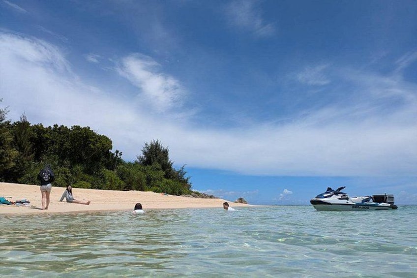 Een strand met mensen die zwemmen, een jetski en een boot. 2