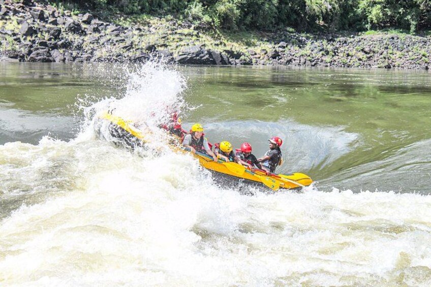 Een groep mensen in een gele raft die een rivier met witte watervallen trotseert. 2